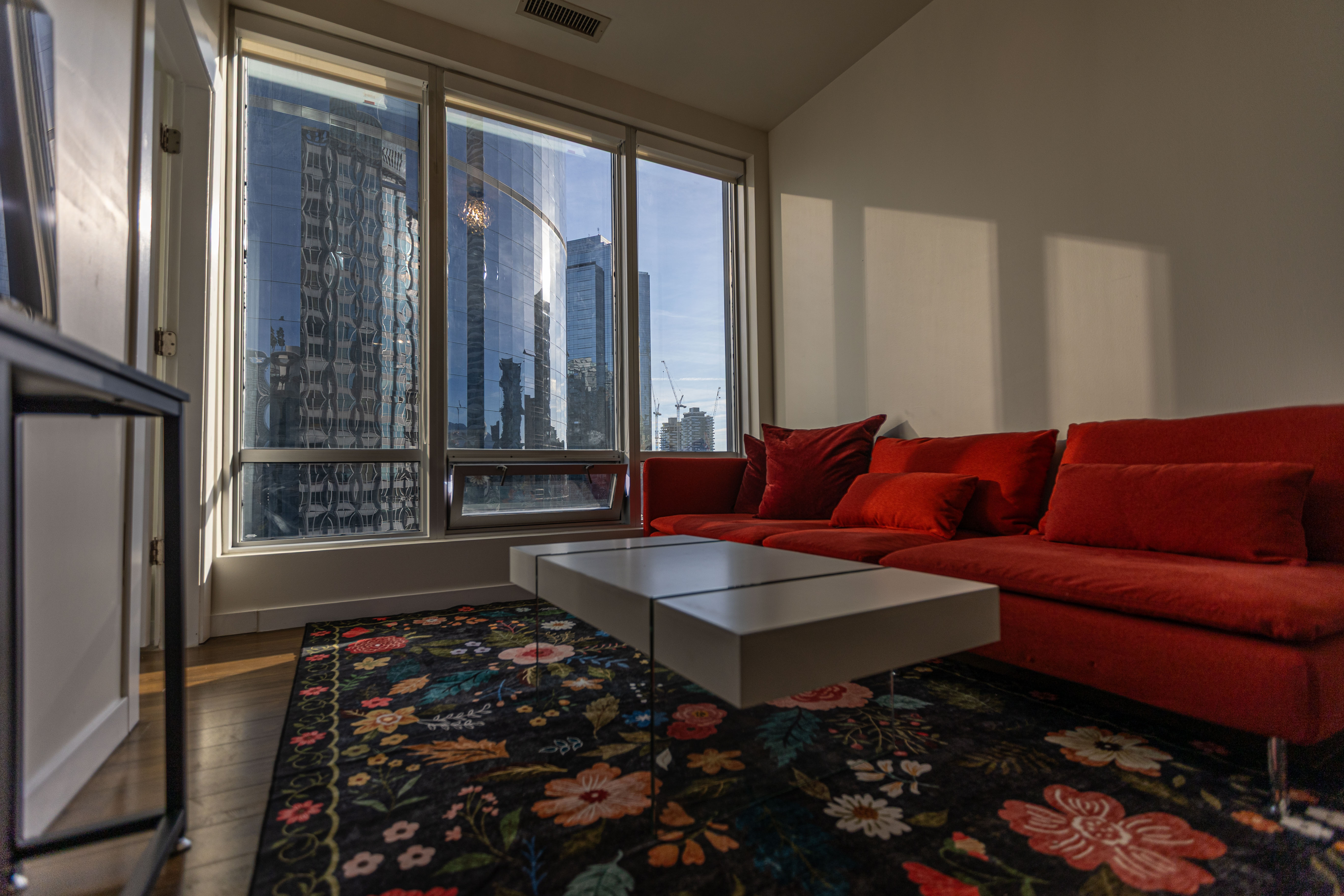 Coco Suite Vancouver living room with large windows and a red sofa